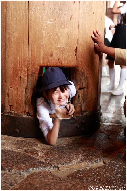 一个小女孩高兴地钻过东大寺里象征幸福的木洞